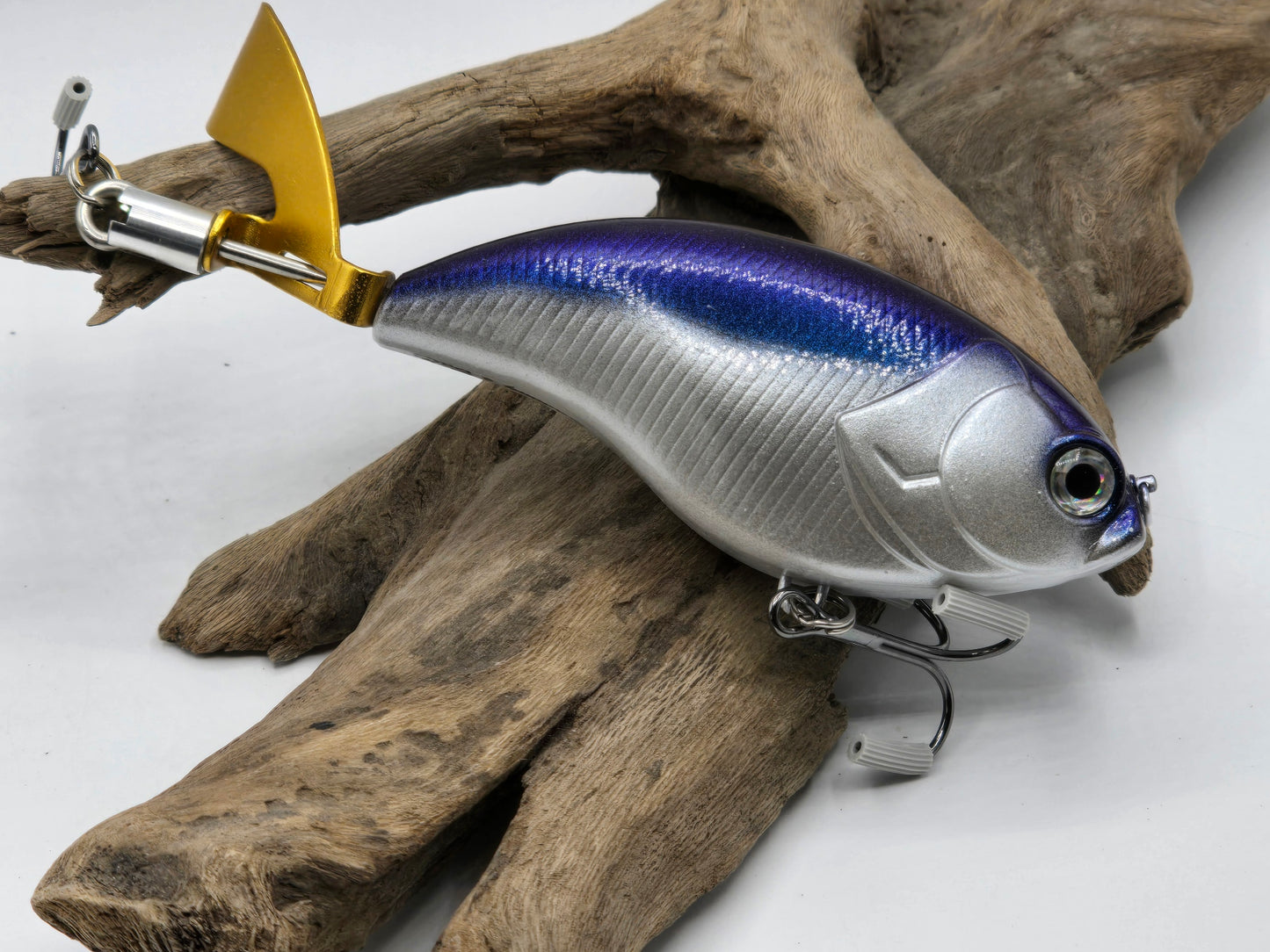A topwater plopping lure that is an alternative to the Deps Evoke zero. Silver body with a Colorshift Blue/Violet back and a gold plopping blade.