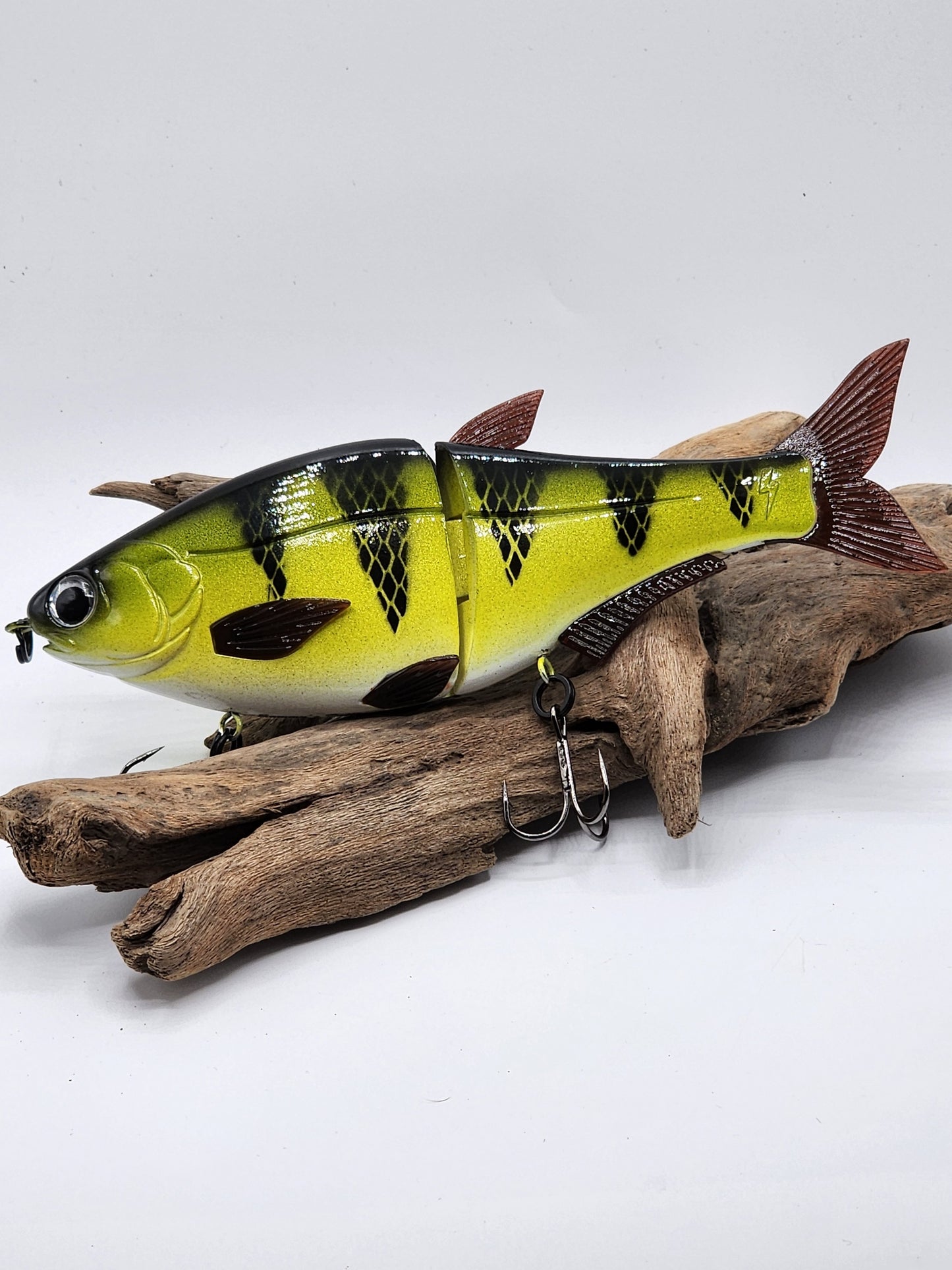 A realistic looking artificial fishing lure designed to resemble a shad, with silver and dark grey body, and a brown tail fin.