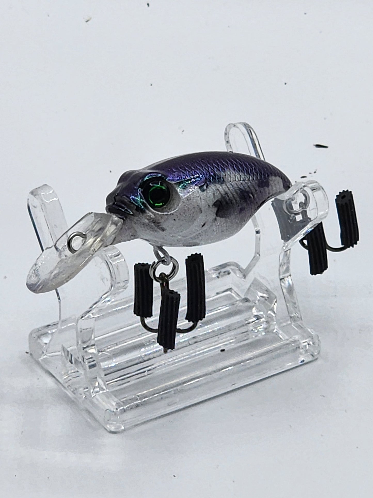 A collection of MegaBass Griffon crankbaits in various colors displayed on a natural wood base, with a quarter beside one of the lures for size comparison.