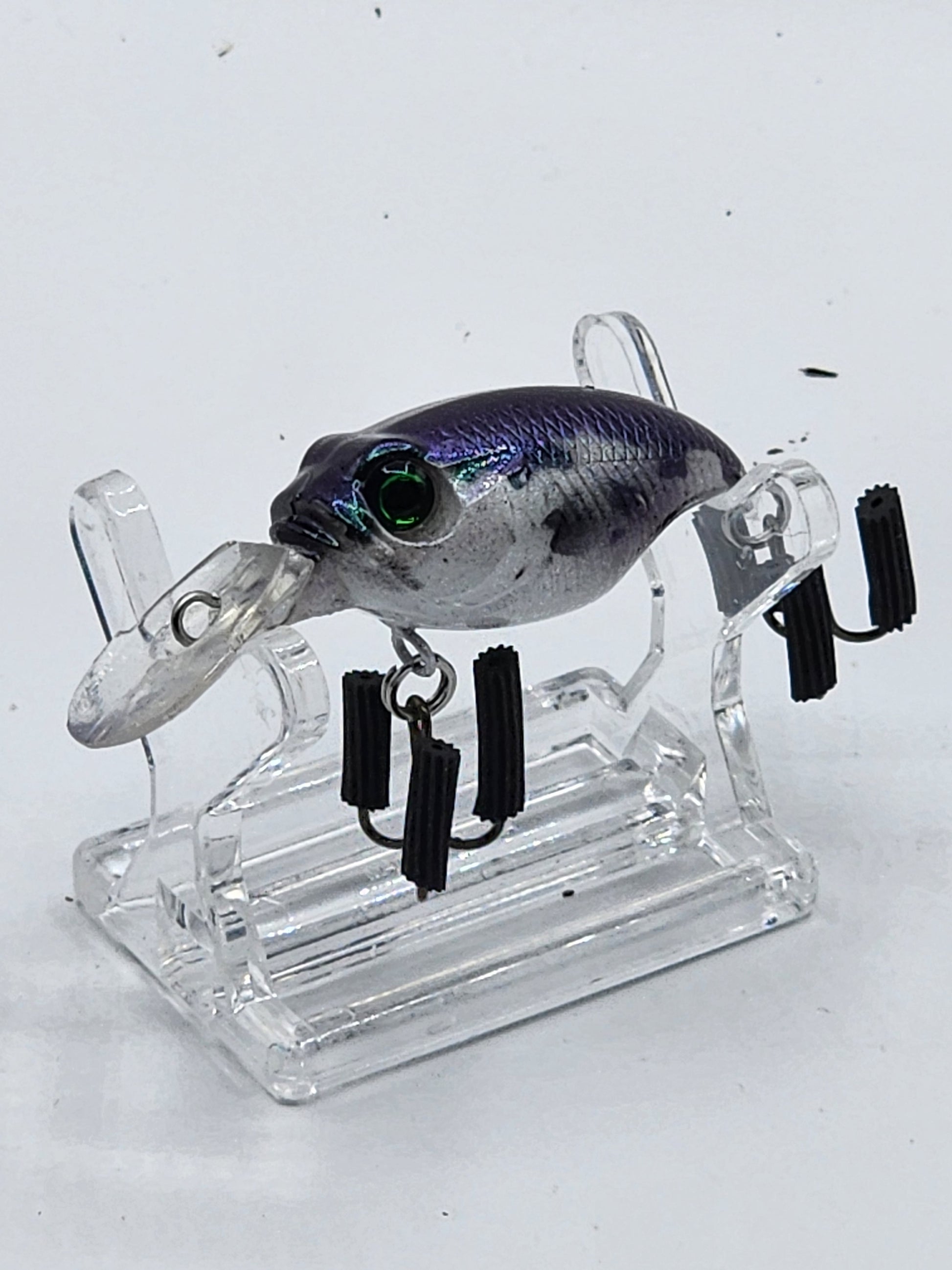 A collection of MegaBass Griffon crankbaits in various colors displayed on a natural wood base, with a quarter beside one of the lures for size comparison.